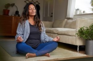 photo of a woman sitting comforatably in her lounge meditating