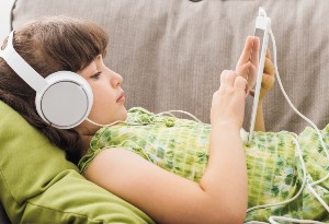 photo of a girl with headphones on playing on a tablet