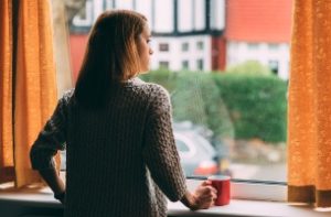 photo of a woman looking out a windoe onto an empty street
