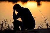 photo of a man sitting and holding his head in his hand